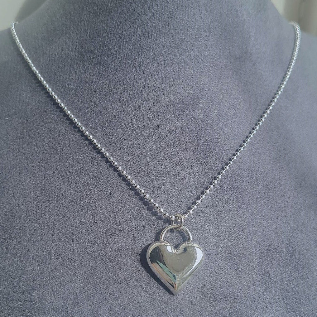 Silver heart-shaped pendant necklace on a mannequin.