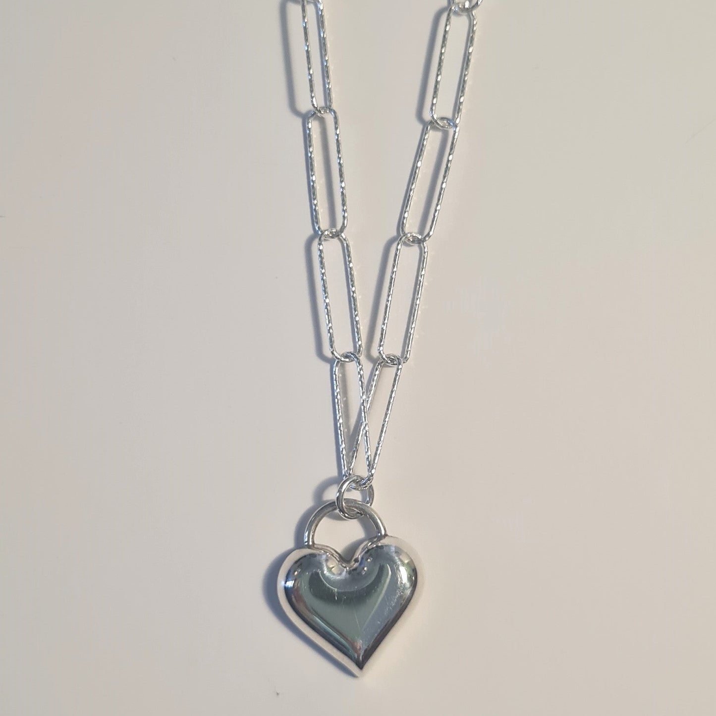 Silver necklace with a heart pendant on a light gray background