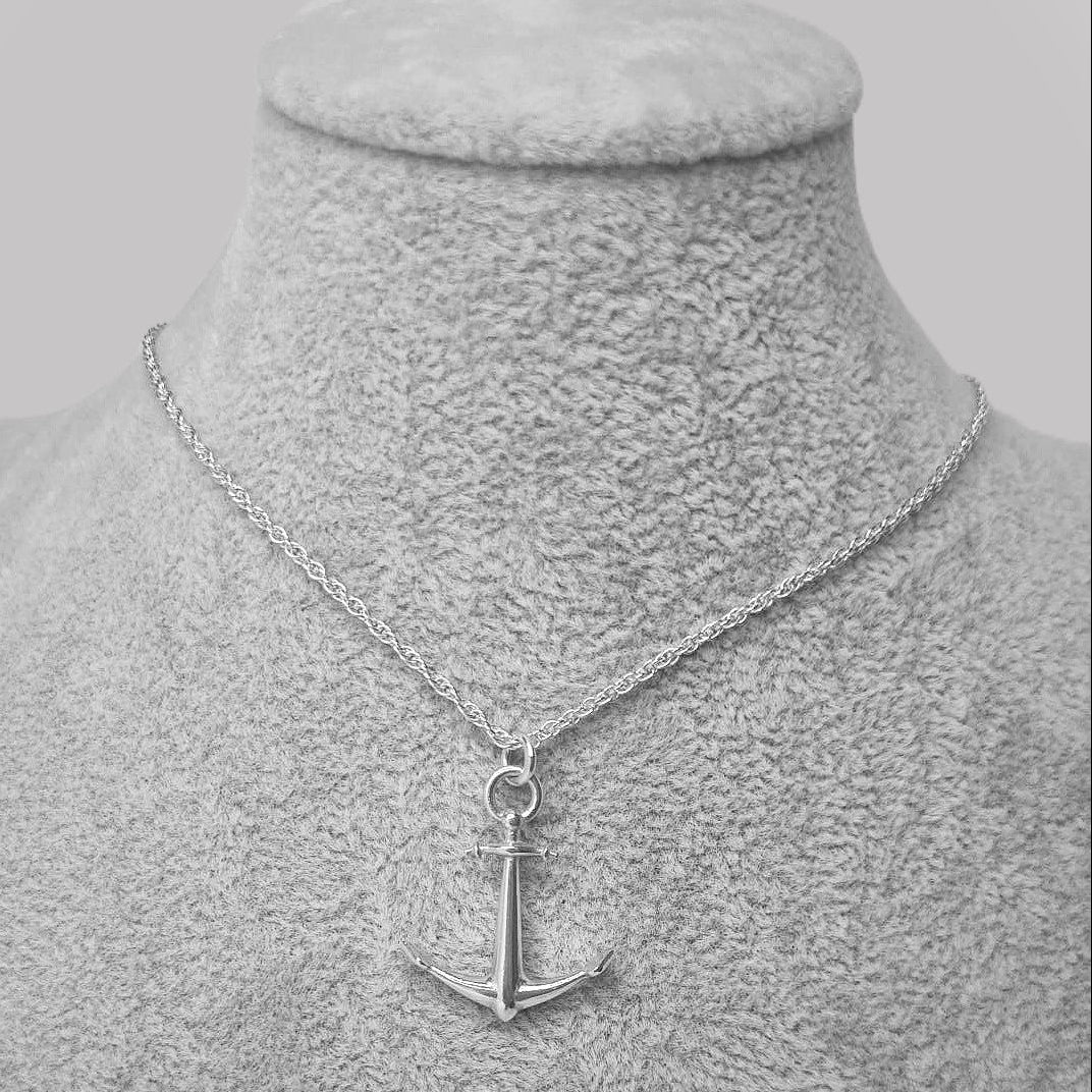 Silver necklace with an anchor pendant on a gray mannequin bust.