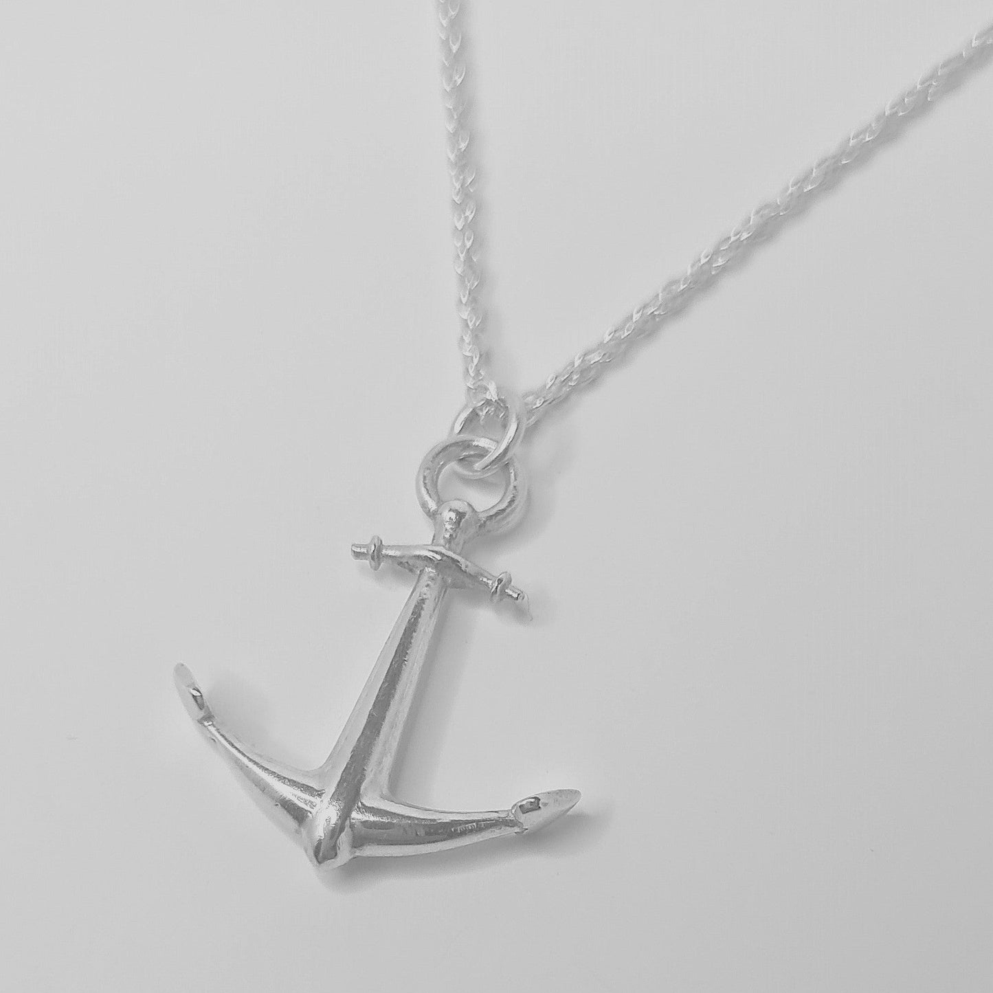 Silver anchor pendant necklace on a light gray background