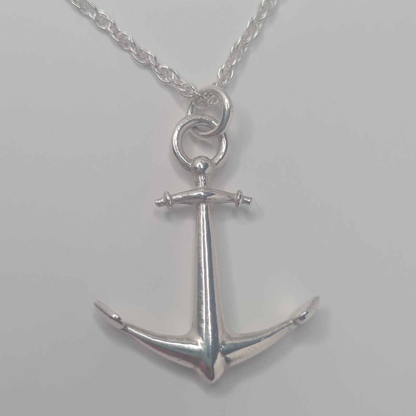 Silver anchor pendant necklace on a gray background