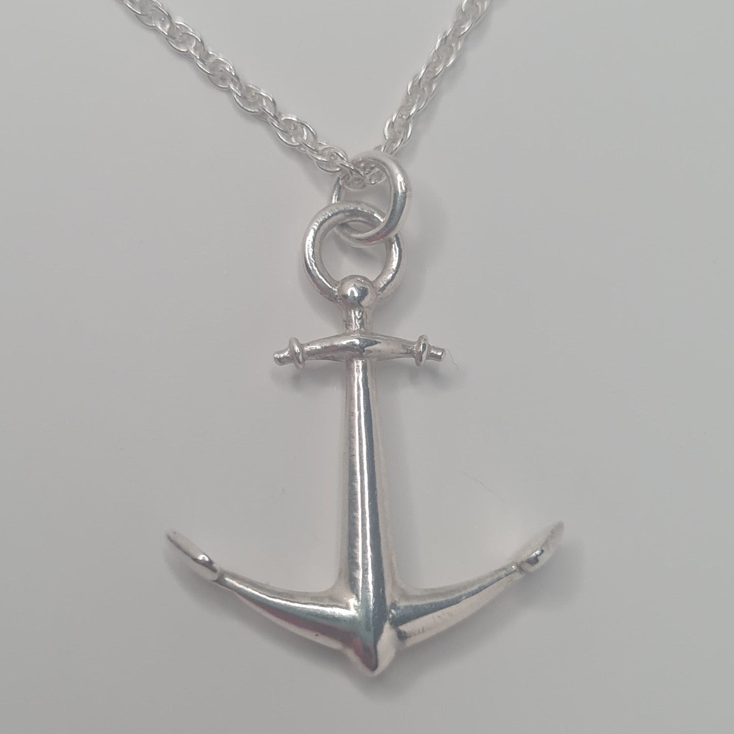 Silver anchor pendant necklace on a gray background