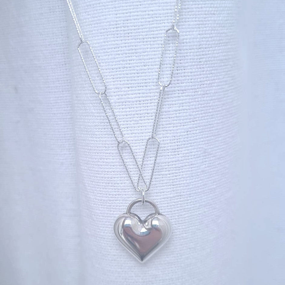Silver heart-shaped pendant necklace on a light blue background