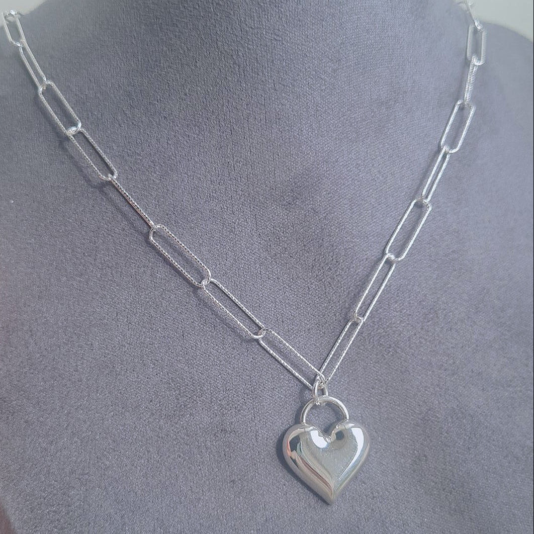 Silver chain necklace with a heart pendant on a mannequin.