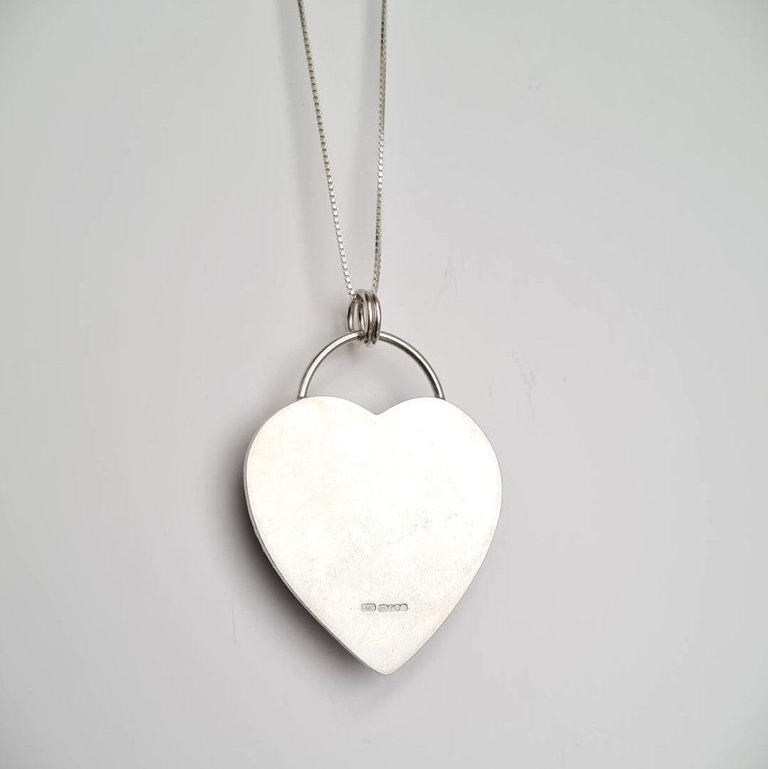 Back of Heart-shaped silver pendant on a chain showing hallmark. 