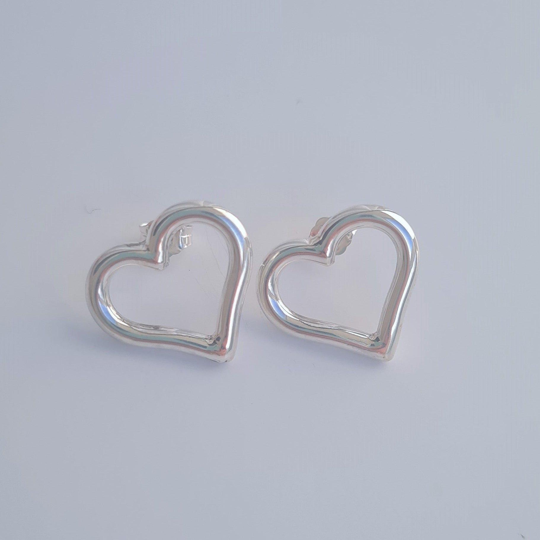 Silver heart-shaped earrings on a light gray background