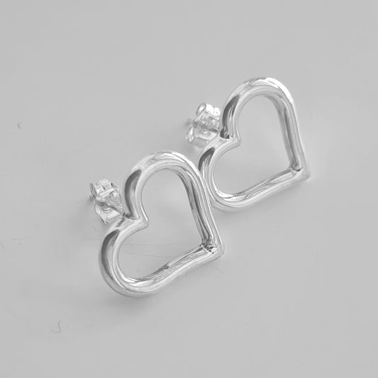 Silver heart-shaped stud earrings on a gray background