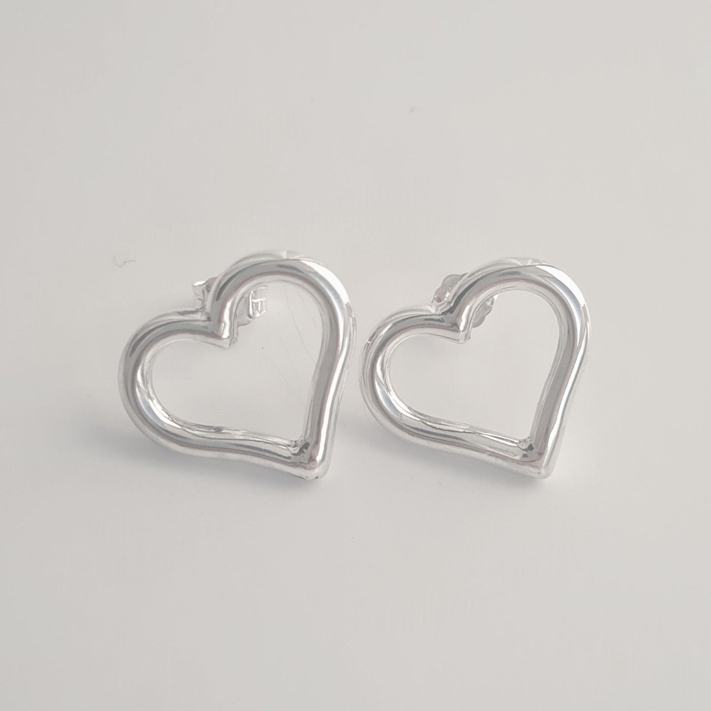 Silver heart-shaped earrings on a light gray background