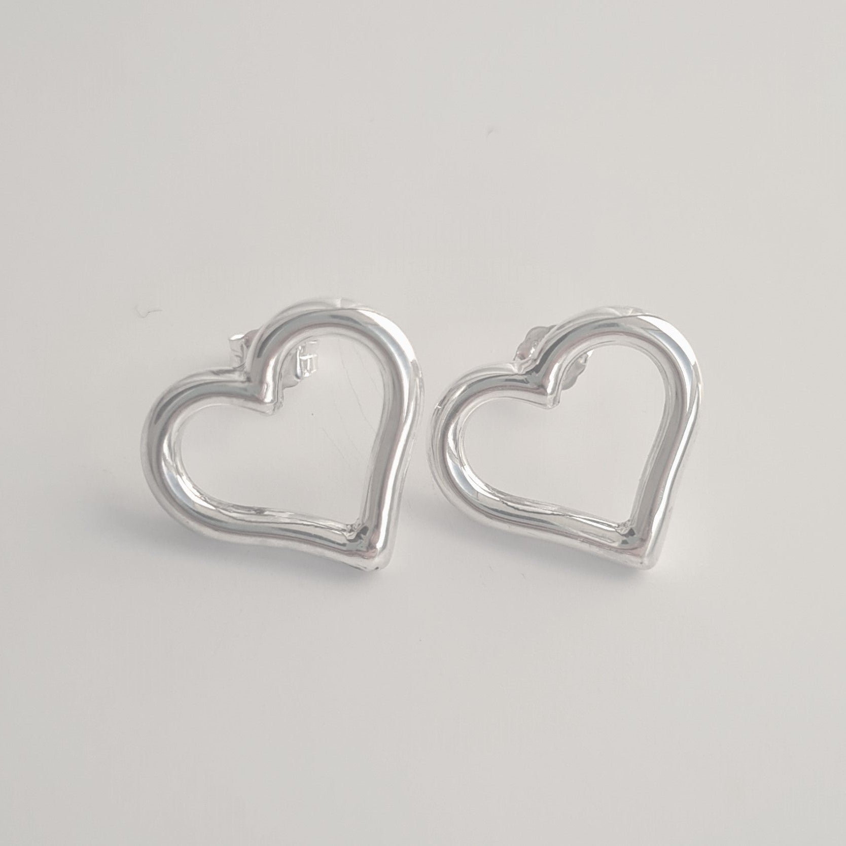 Silver heart-shaped earrings on a light gray background