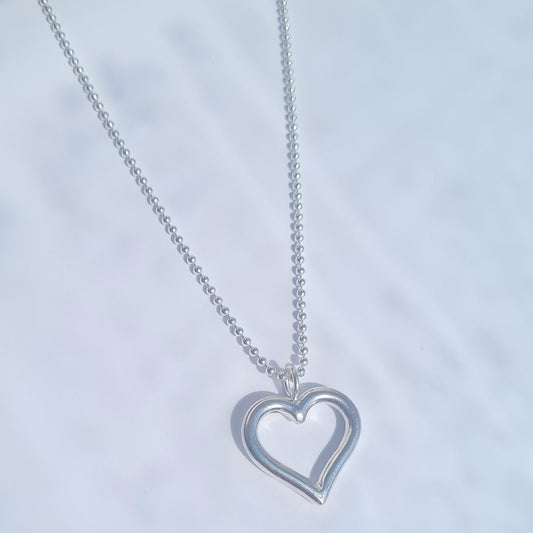 Silver heart-shaped pendant necklace on a light gray background