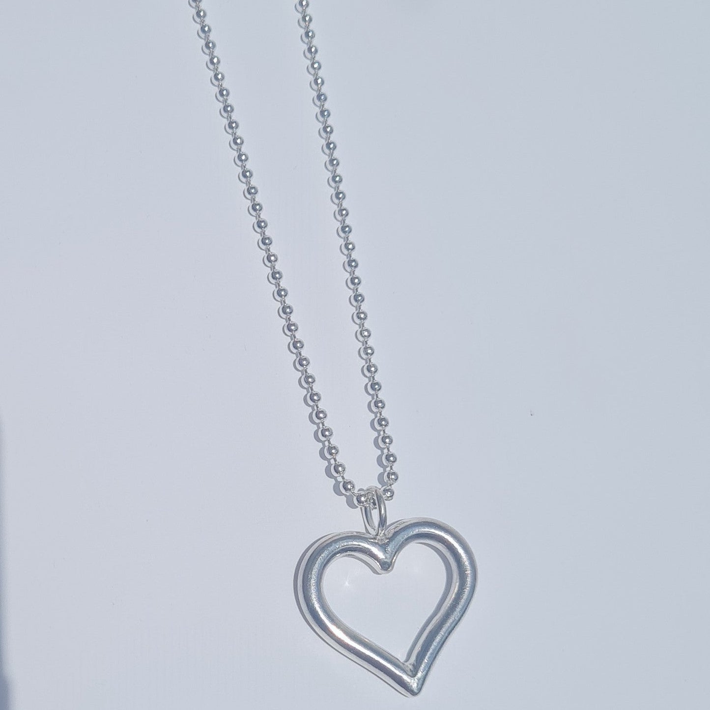 Silver heart-shaped pendant necklace on a light gray background