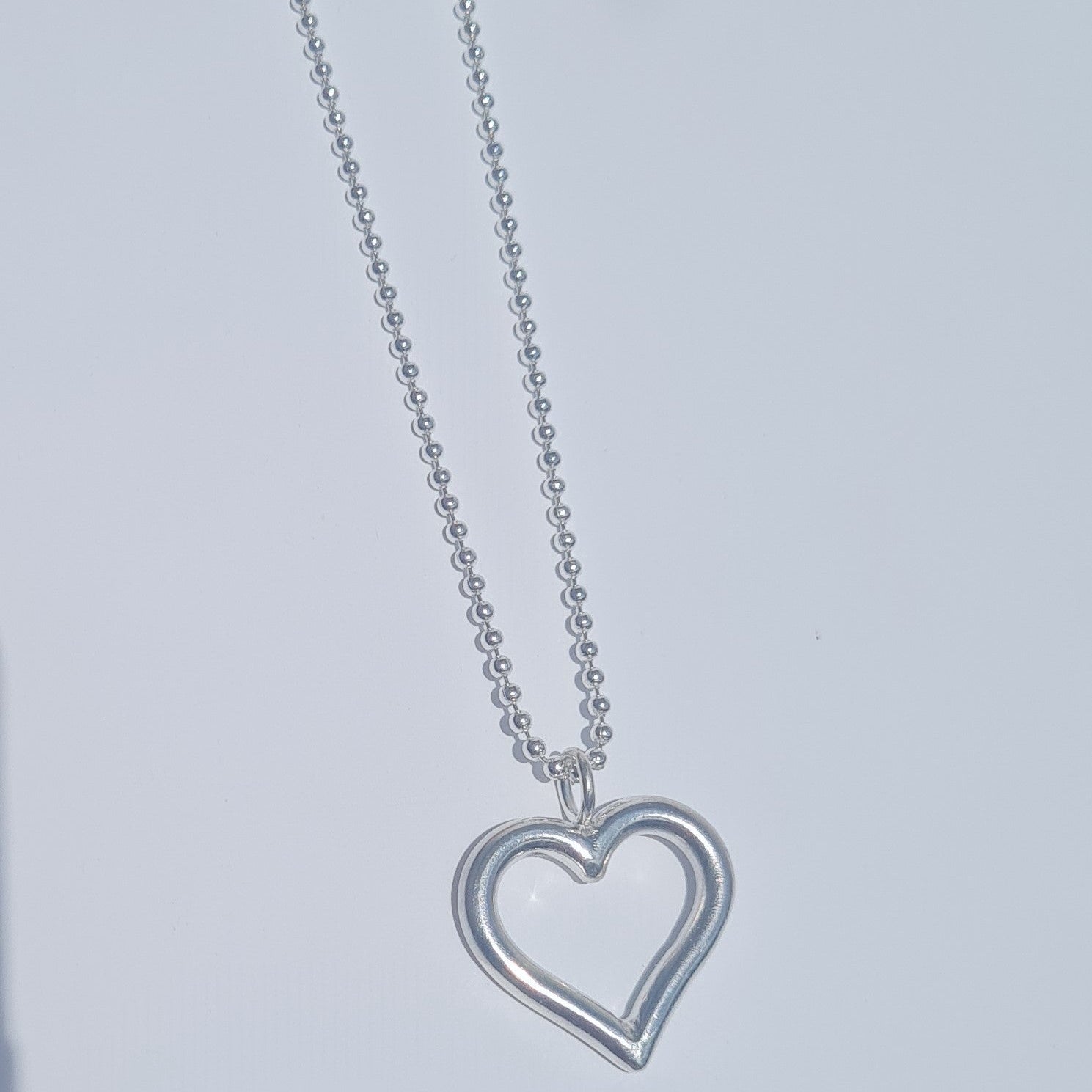 Silver heart-shaped pendant necklace on a light gray background