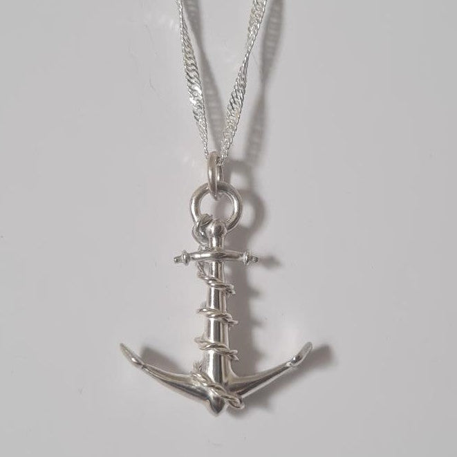 A silver anchor pendant necklace on a delicate silver chain, displayed against a plain light gray background.